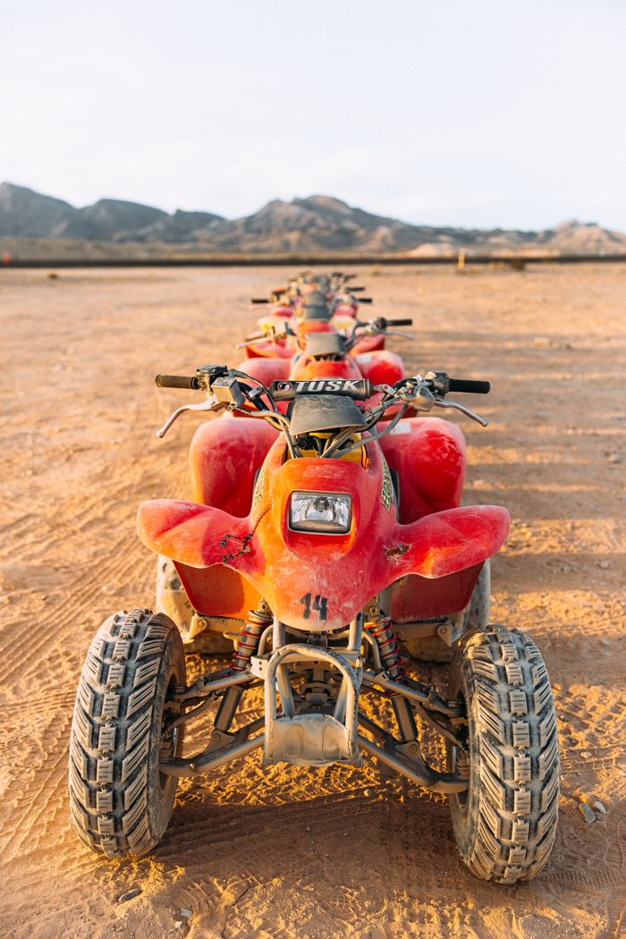 A row of red ATVs lined up on the sandy desert terrain in Las Vegas, Nevada under clear skies.