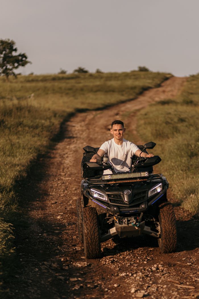 A man enjoying a ride on a quad bike along a scenic countryside trail on a sunny day.